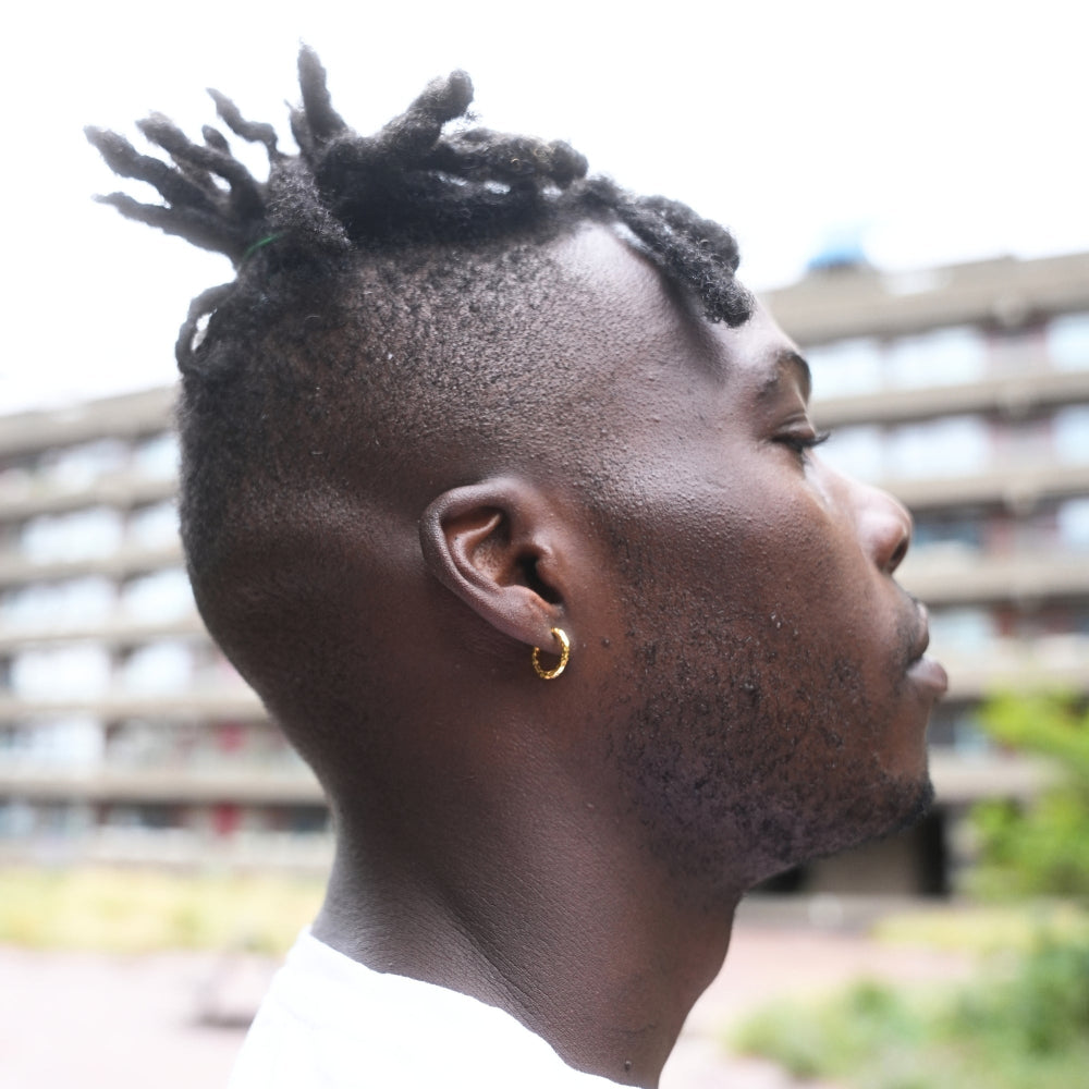 Man with styled hair and earring looking away from the camera