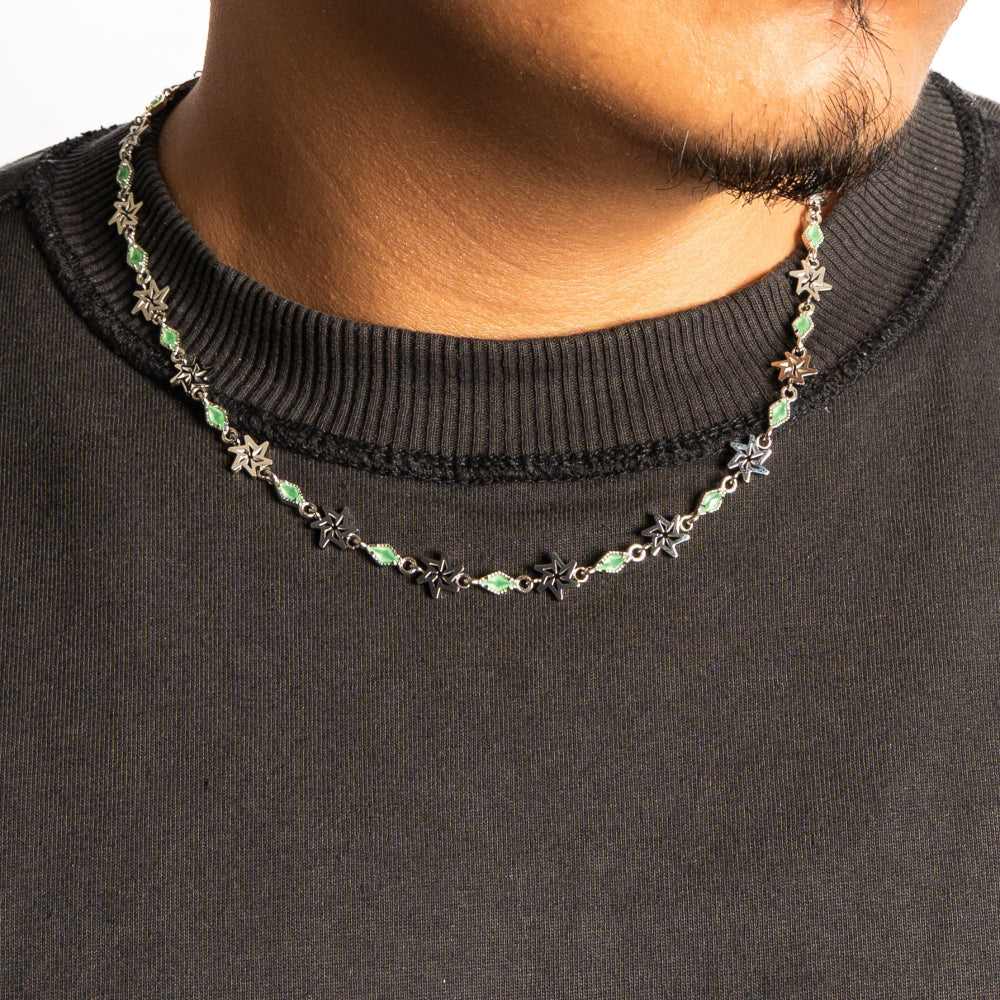 Necklace with green beads worn by a person on a black shirt