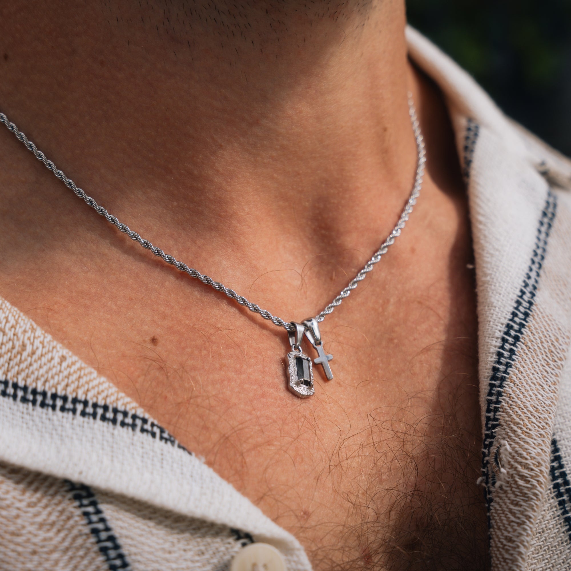 Close-up of a person wearing a silver necklace with a pendant.