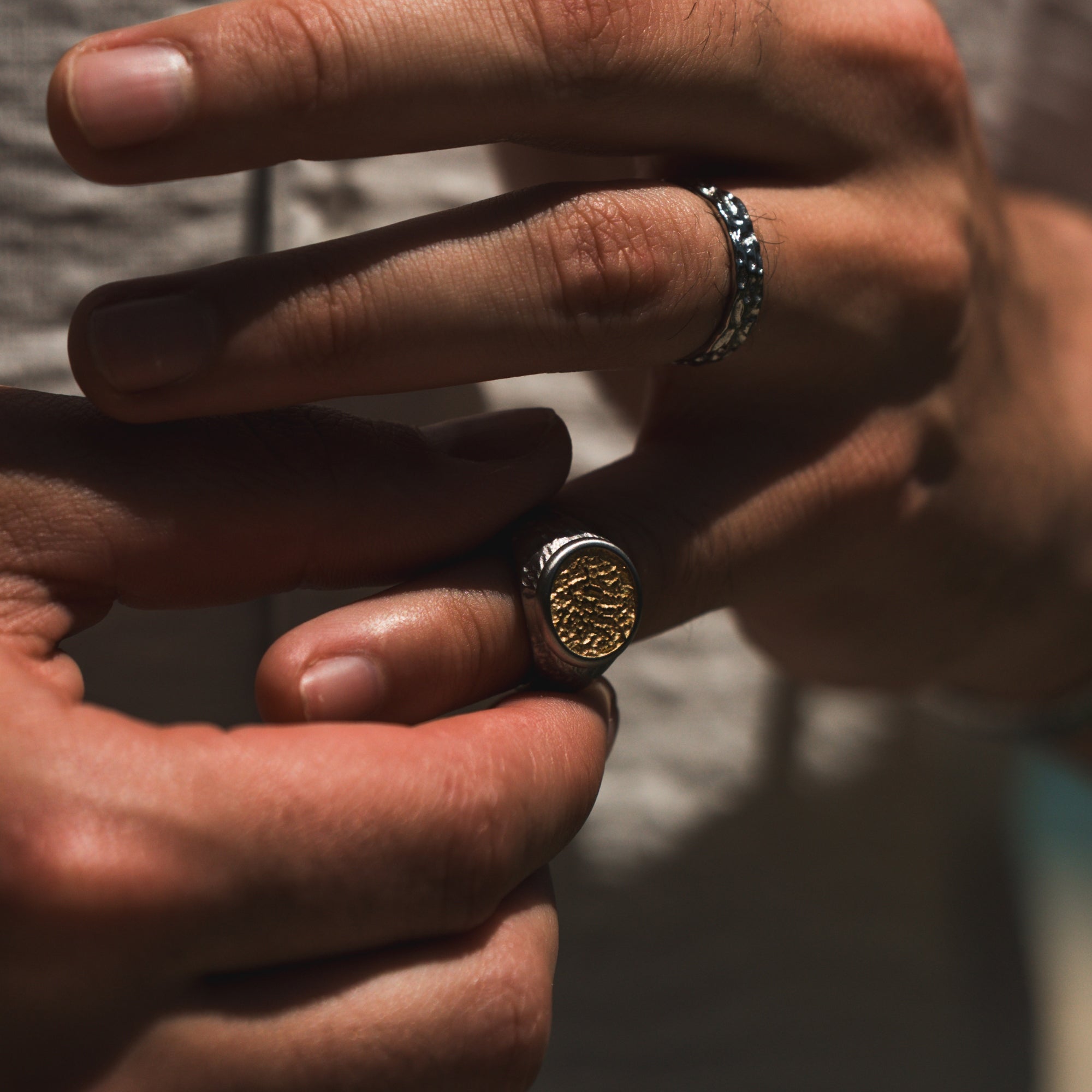 Close-up of hands wearing two rings with detailed designs.