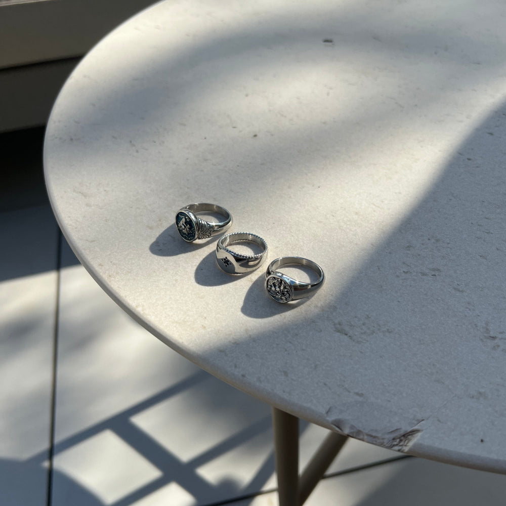 Three silver rings on a textured white surface with shadows.