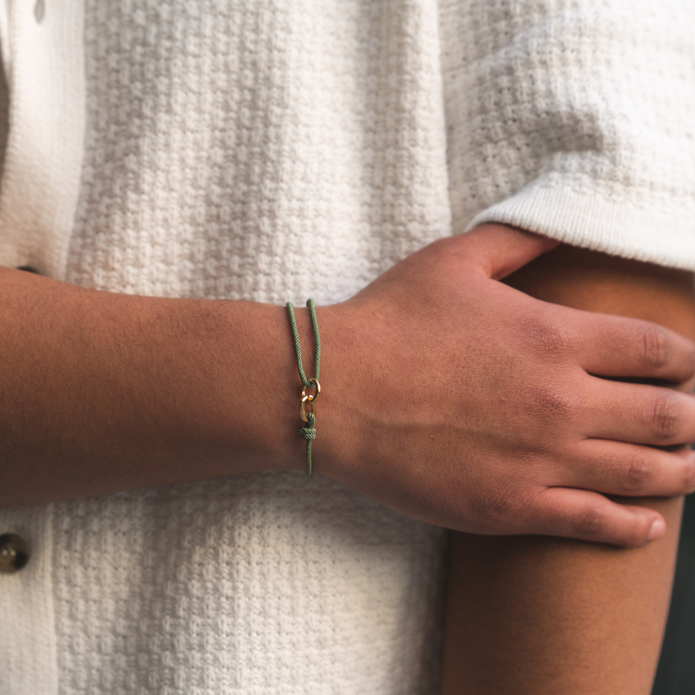 Close-up of a person's wrist wearing a green bracelet with a neutral background