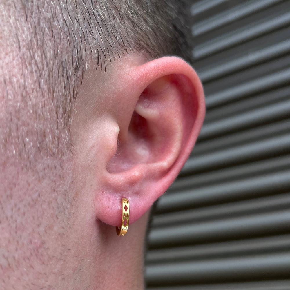 Gold hoop earring worn by a person with a neutral background