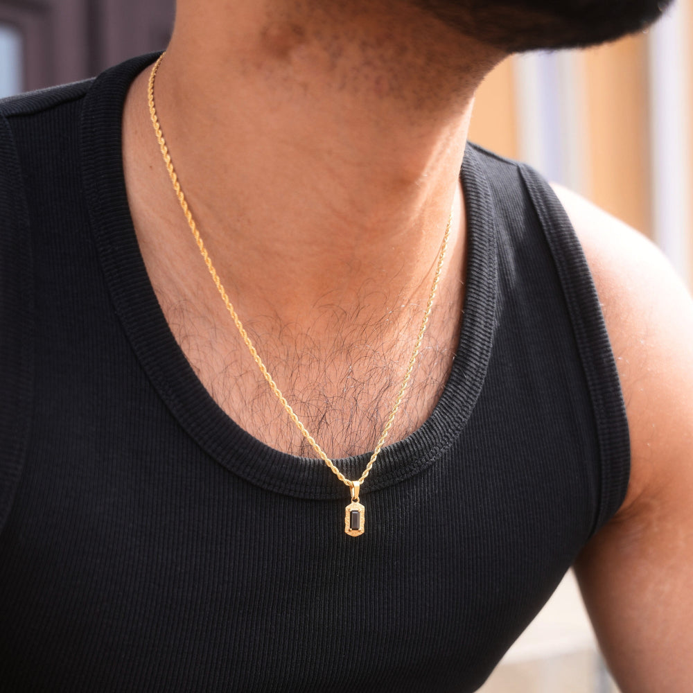 Person wearing a gold necklace with a pendant on a blurred background