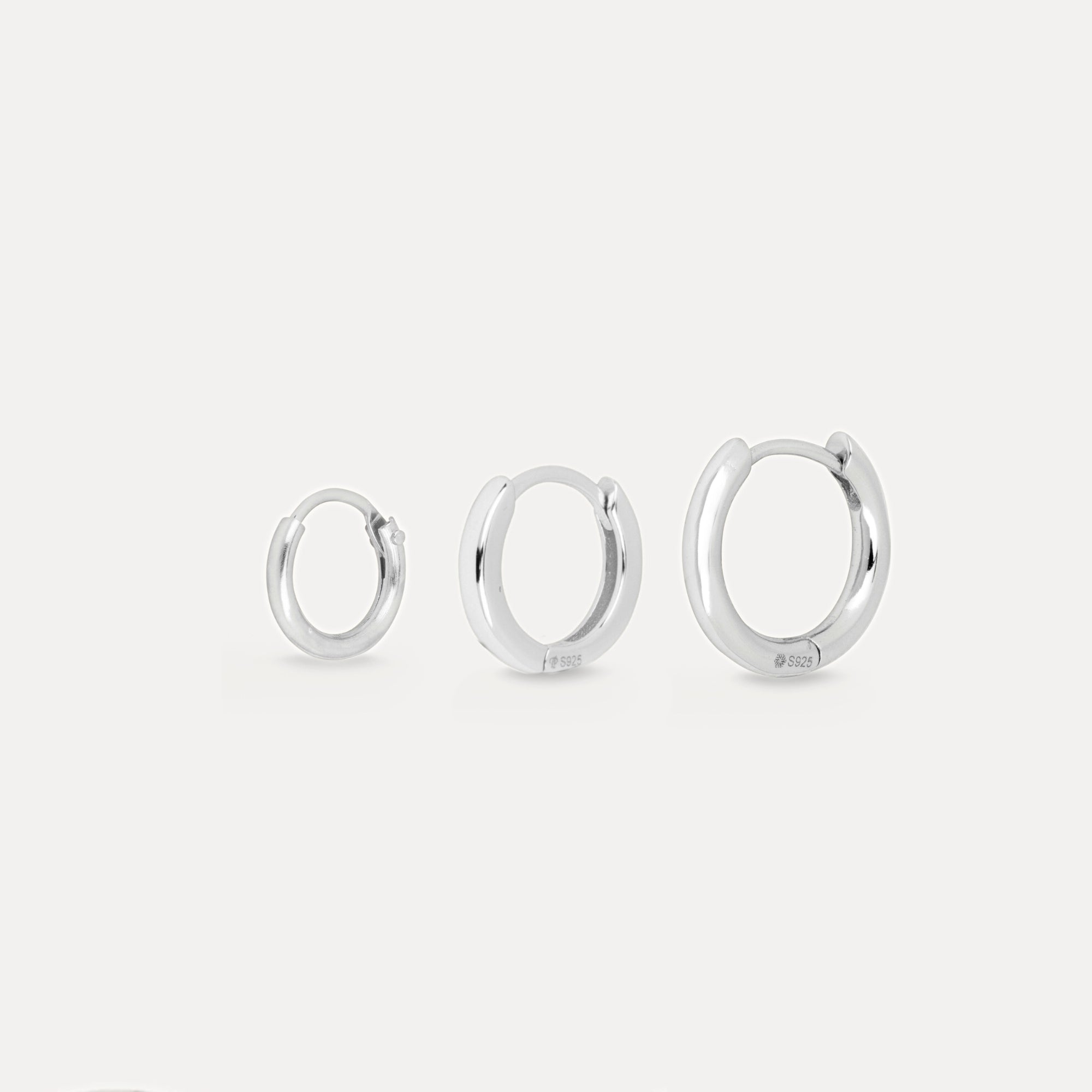Three pairs of silver hoop earrings on a white background
