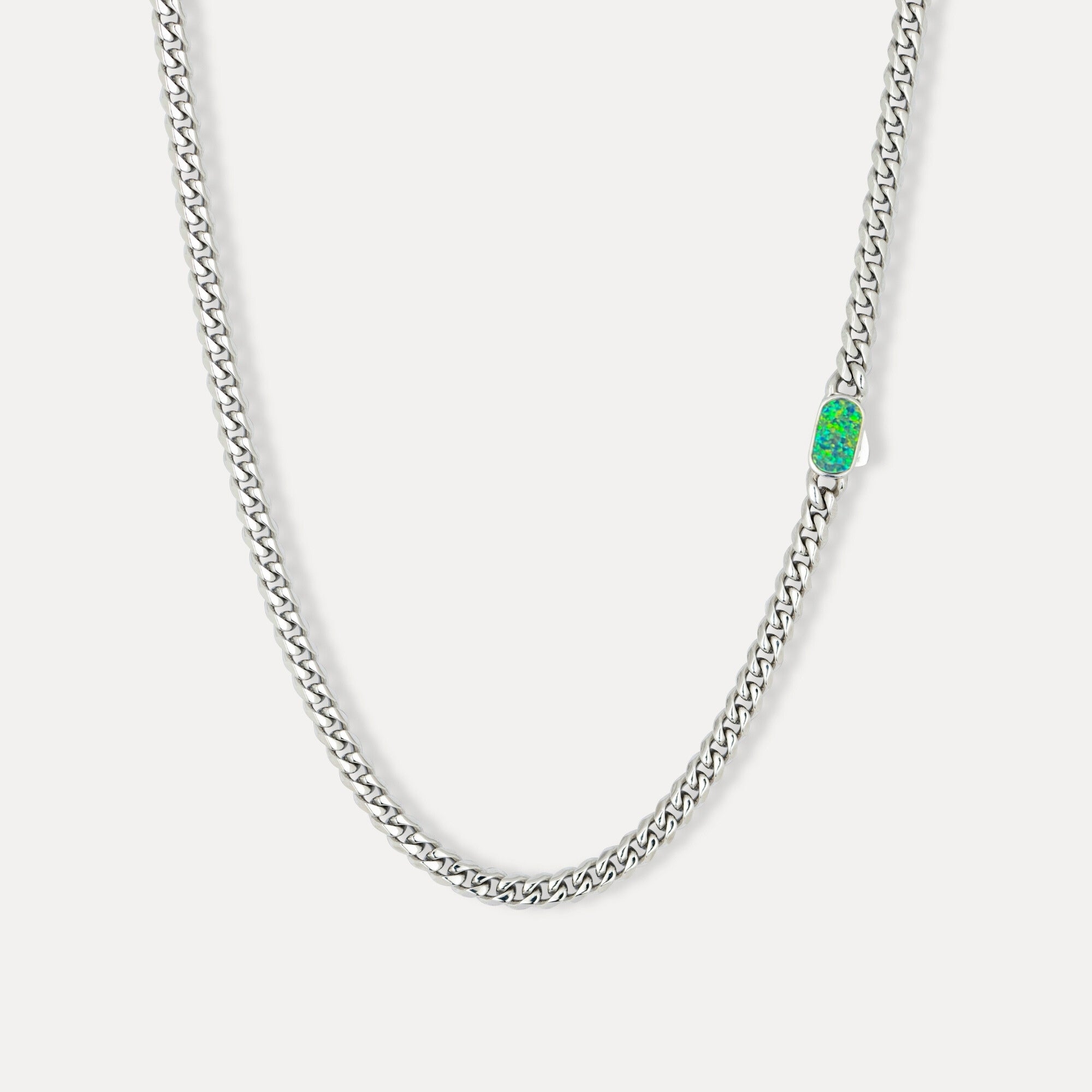 Silver chain necklace with a green gemstone pendant on a white background
