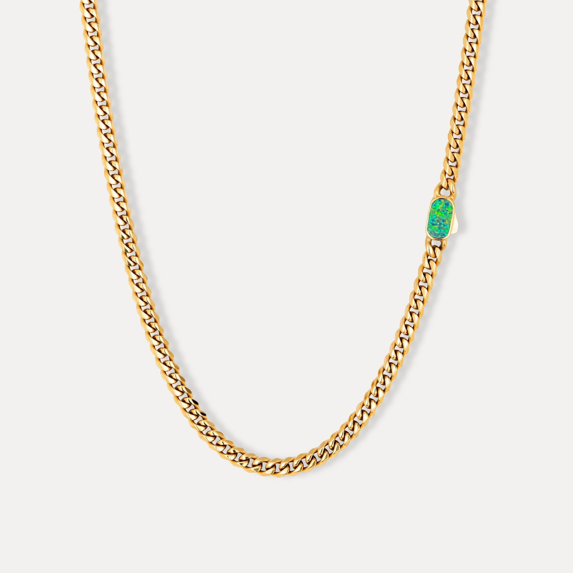 Gold chain necklace with a green gemstone on a white background