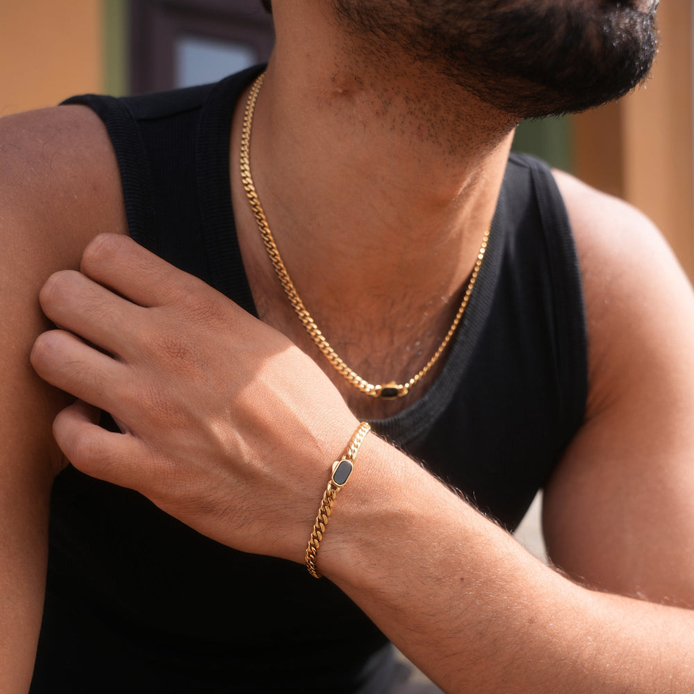 Person wearing a gold chain necklace and bracelet on a blurred background