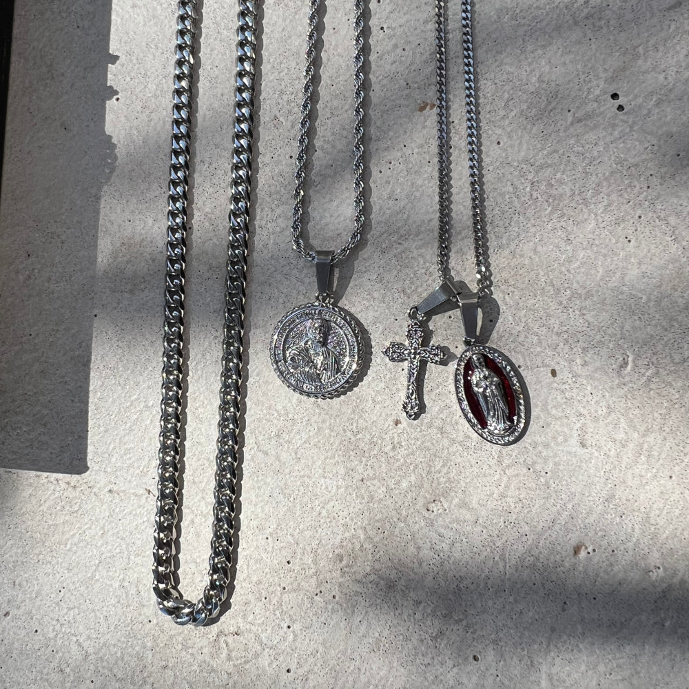 Three silver necklaces with pendants on a textured surface