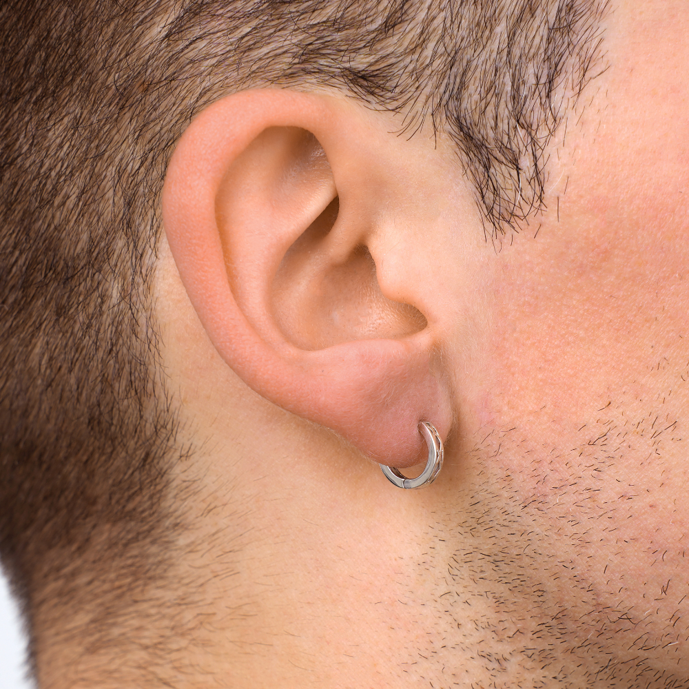 Close-up of a man's ear wearing a silver hoop earring.