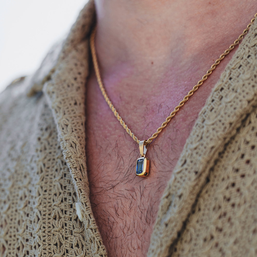 Gold necklace with a pendant worn by a person, close-up on neck and chest.