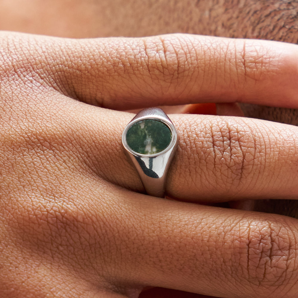 Silver ring with a green stone on a person's finger