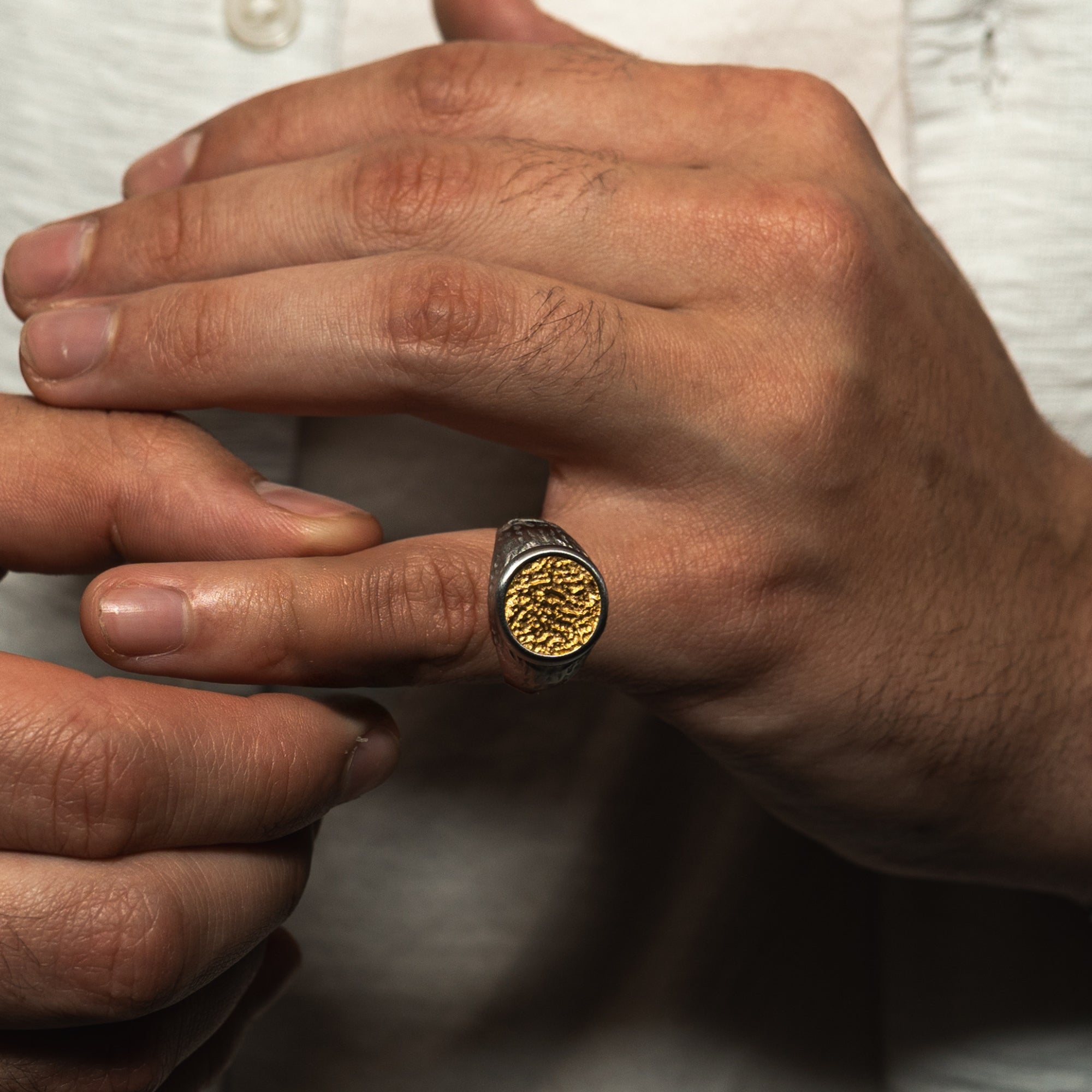 Close-up of a hand wearing a gold ring with a textured band.