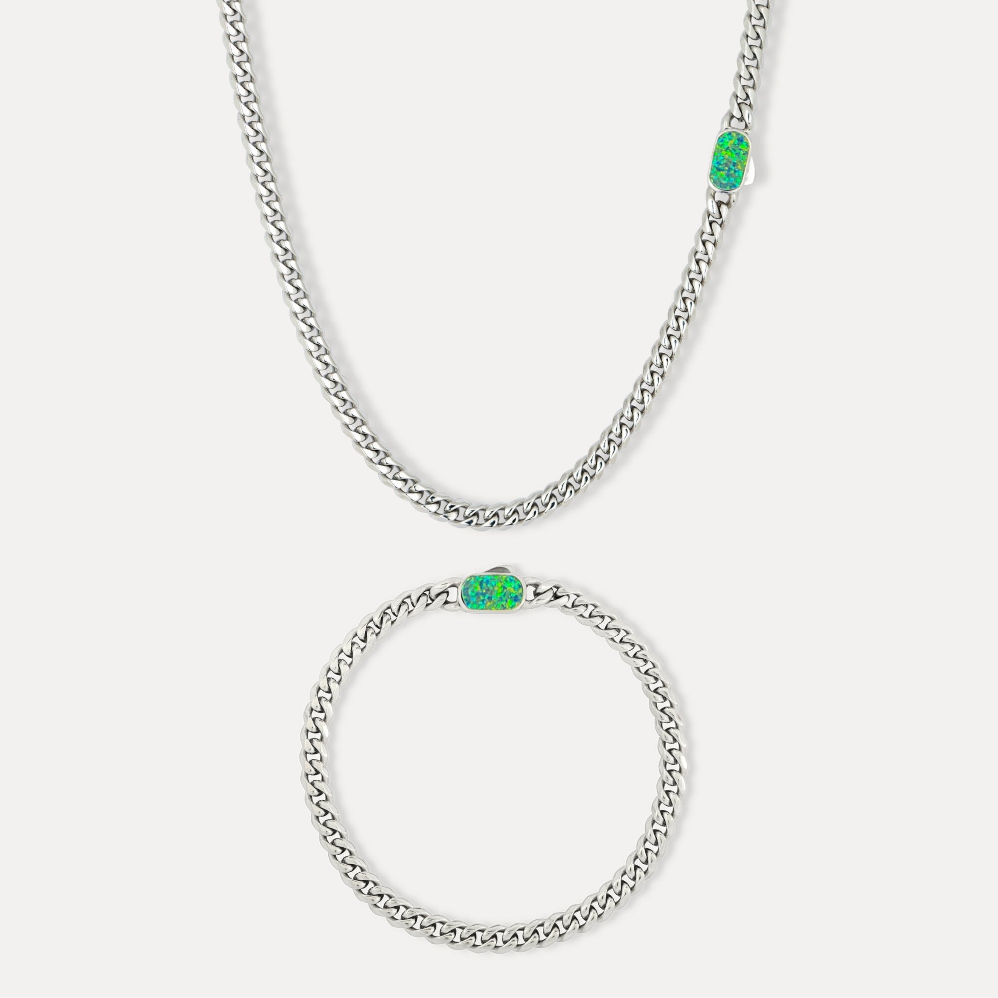 Silver chain necklace with green gemstones on a white background