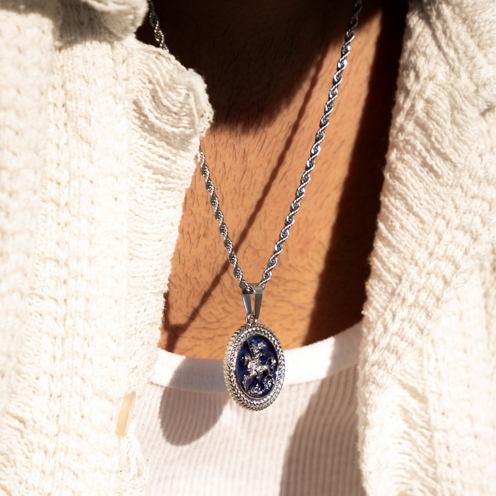 Silver necklace with a blue pendant on a textured white background