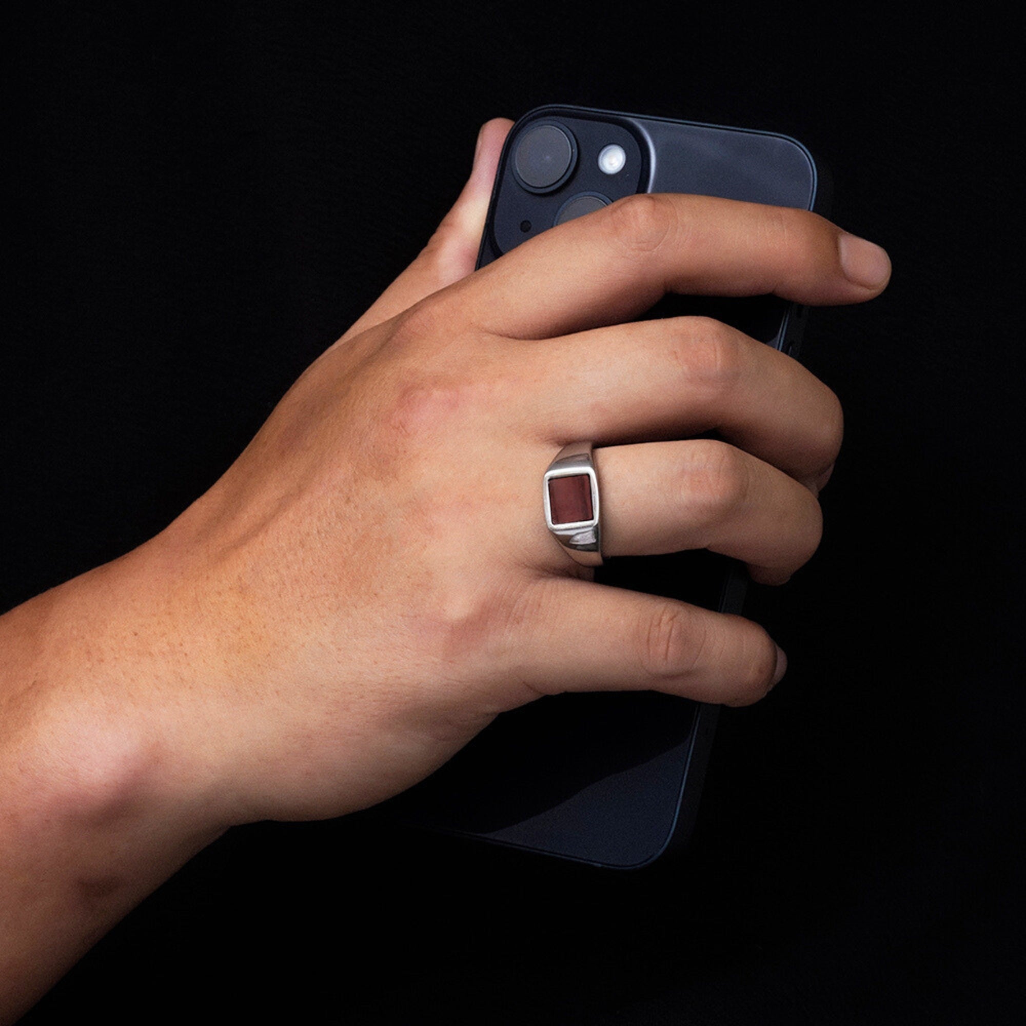 Hand holding a smartphone with a dark background