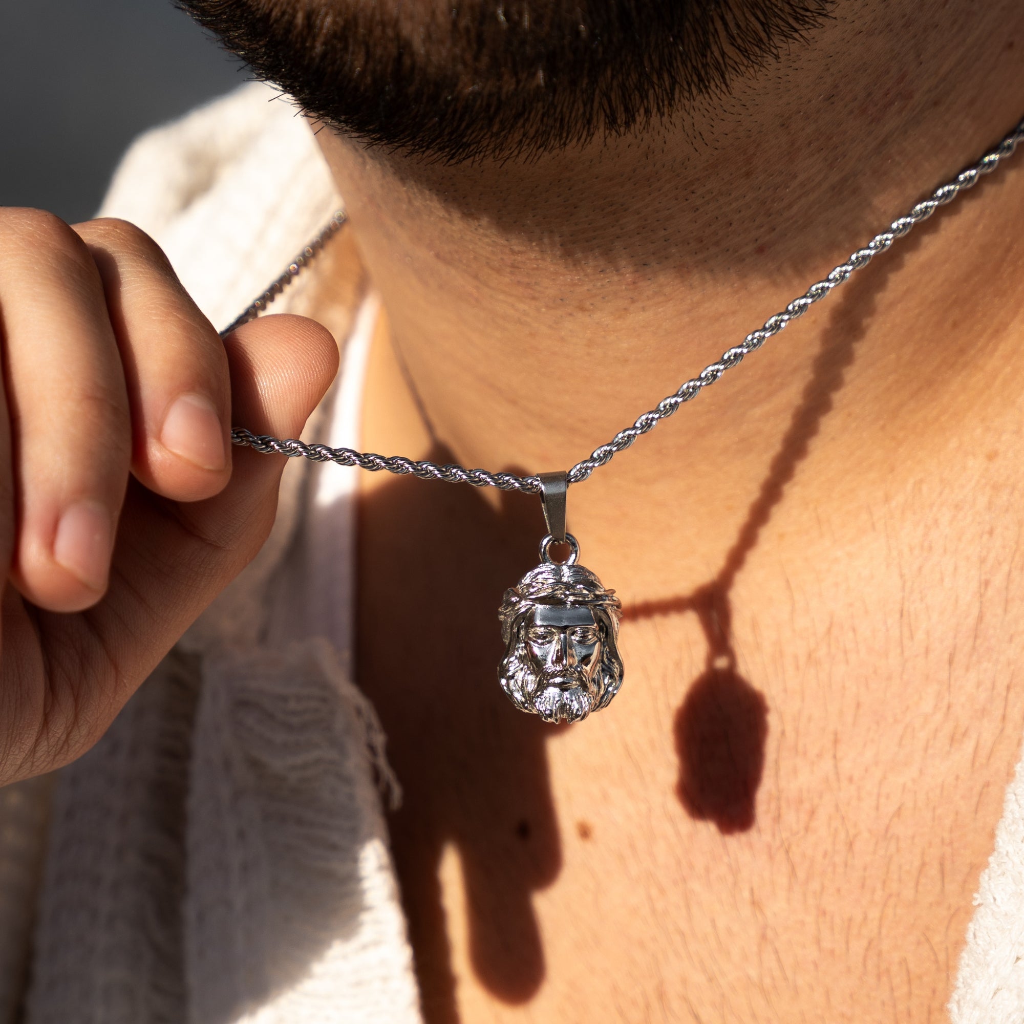 Close-up of a person wearing a silver necklace with a pendant.