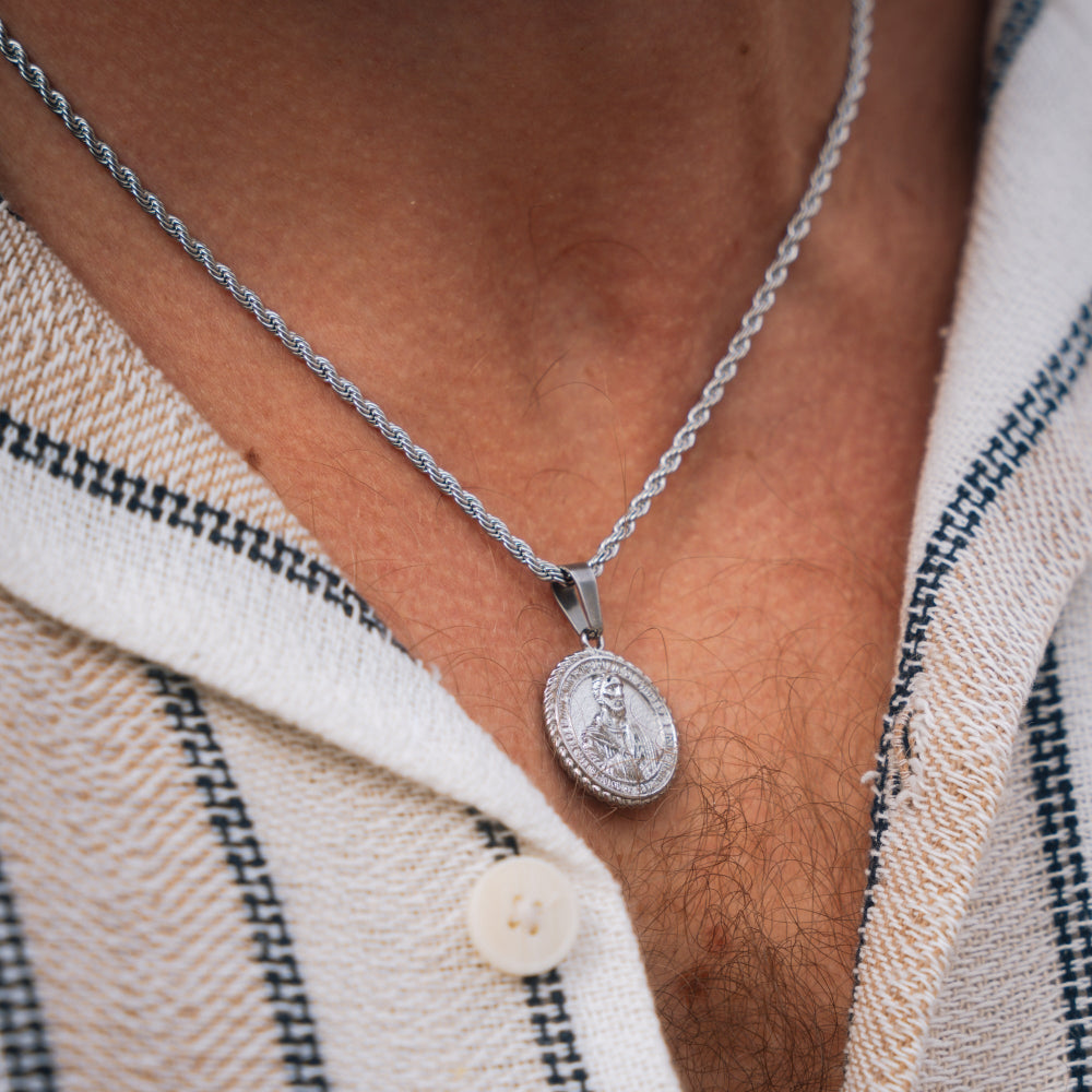 Silver necklace with a pendant worn by a person against a textured fabric background