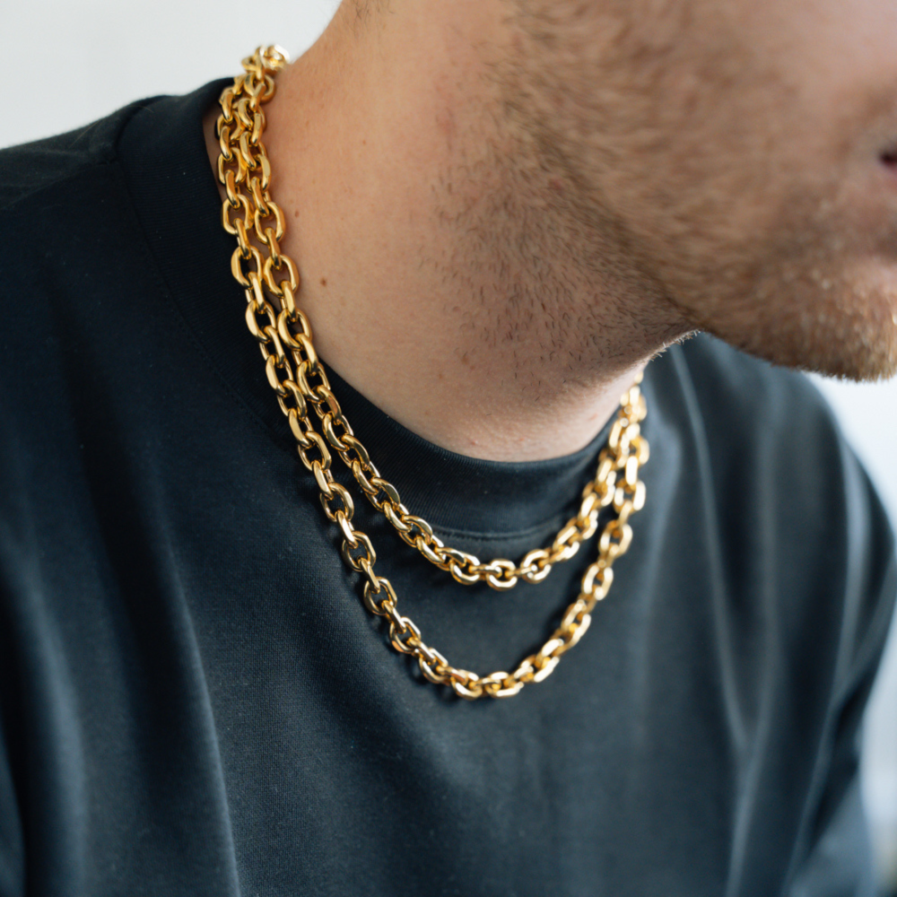 Person wearing a gold chain necklace against a neutral background