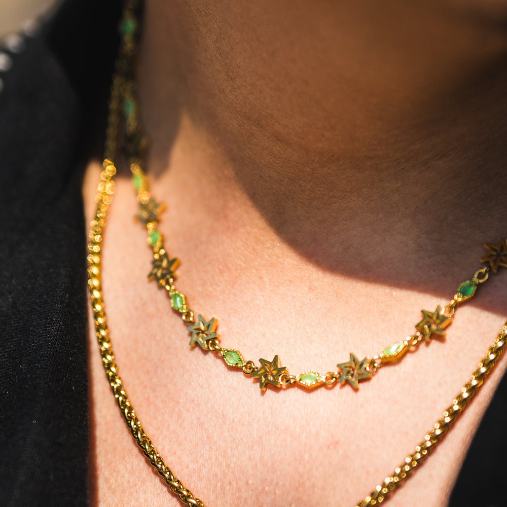 Close-up of a person wearing a gold necklace with star-shaped beads.