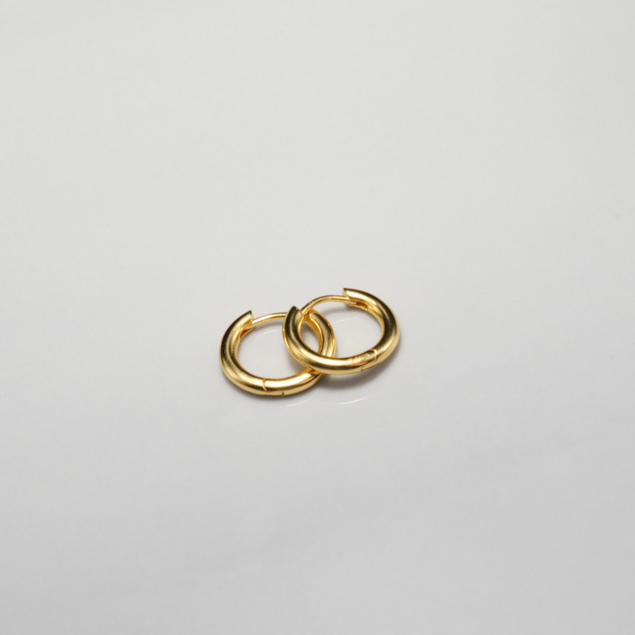 Pair of gold hoop earrings on a light gray background
