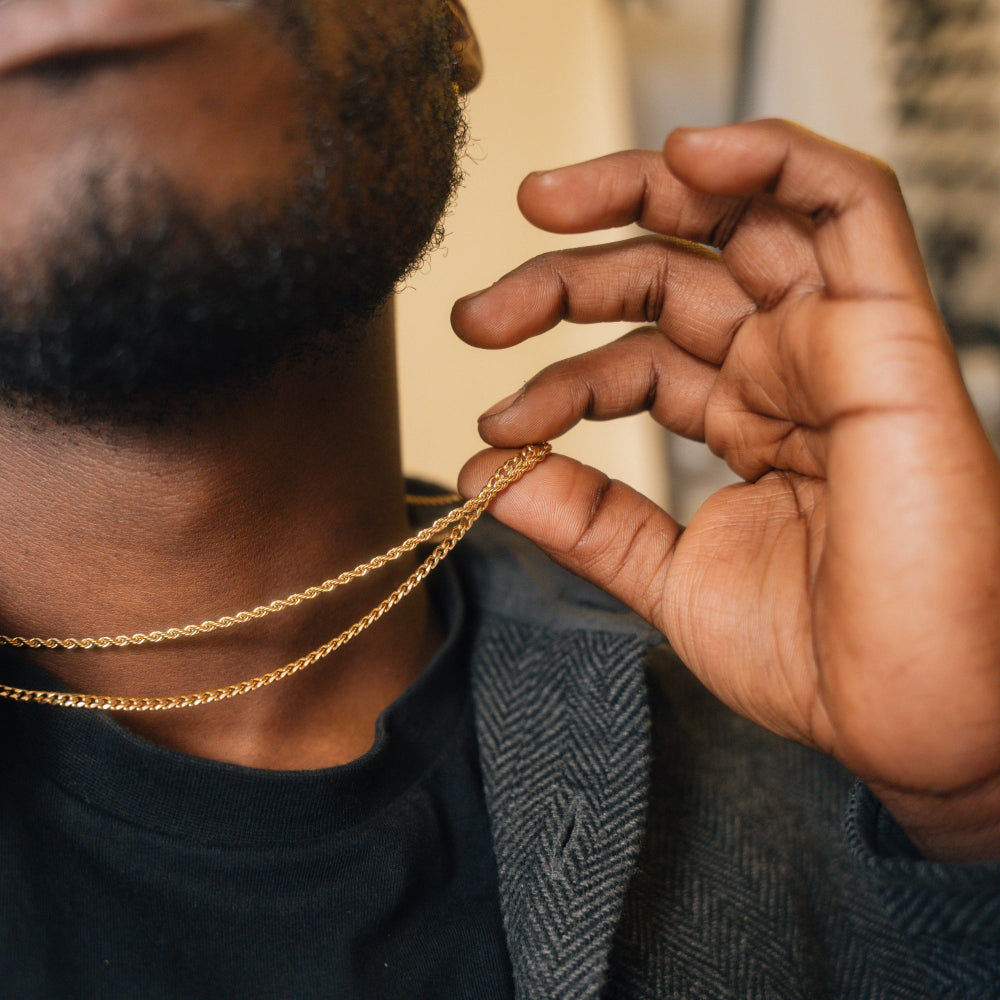 Person adjusting a gold chain necklace with a blurred background