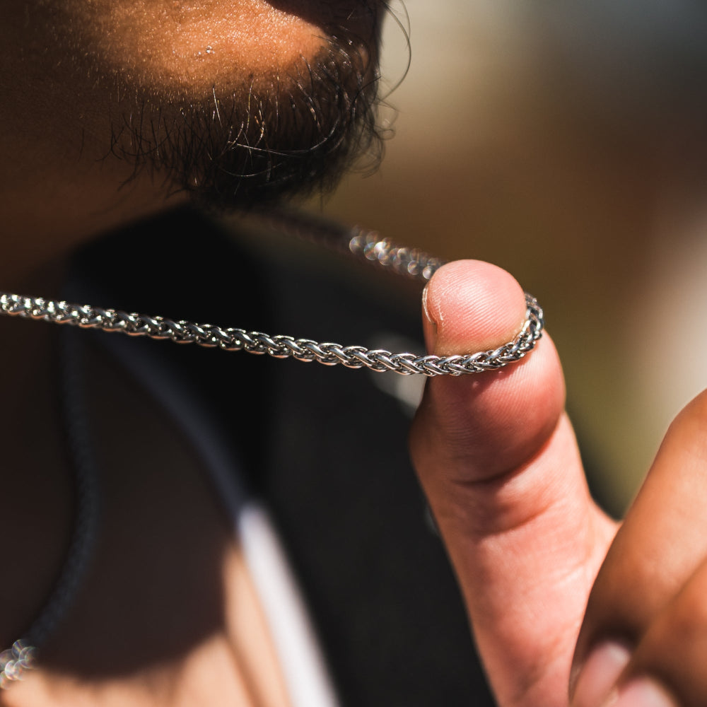 Hand holding a silver chain necklace with a blurred background
