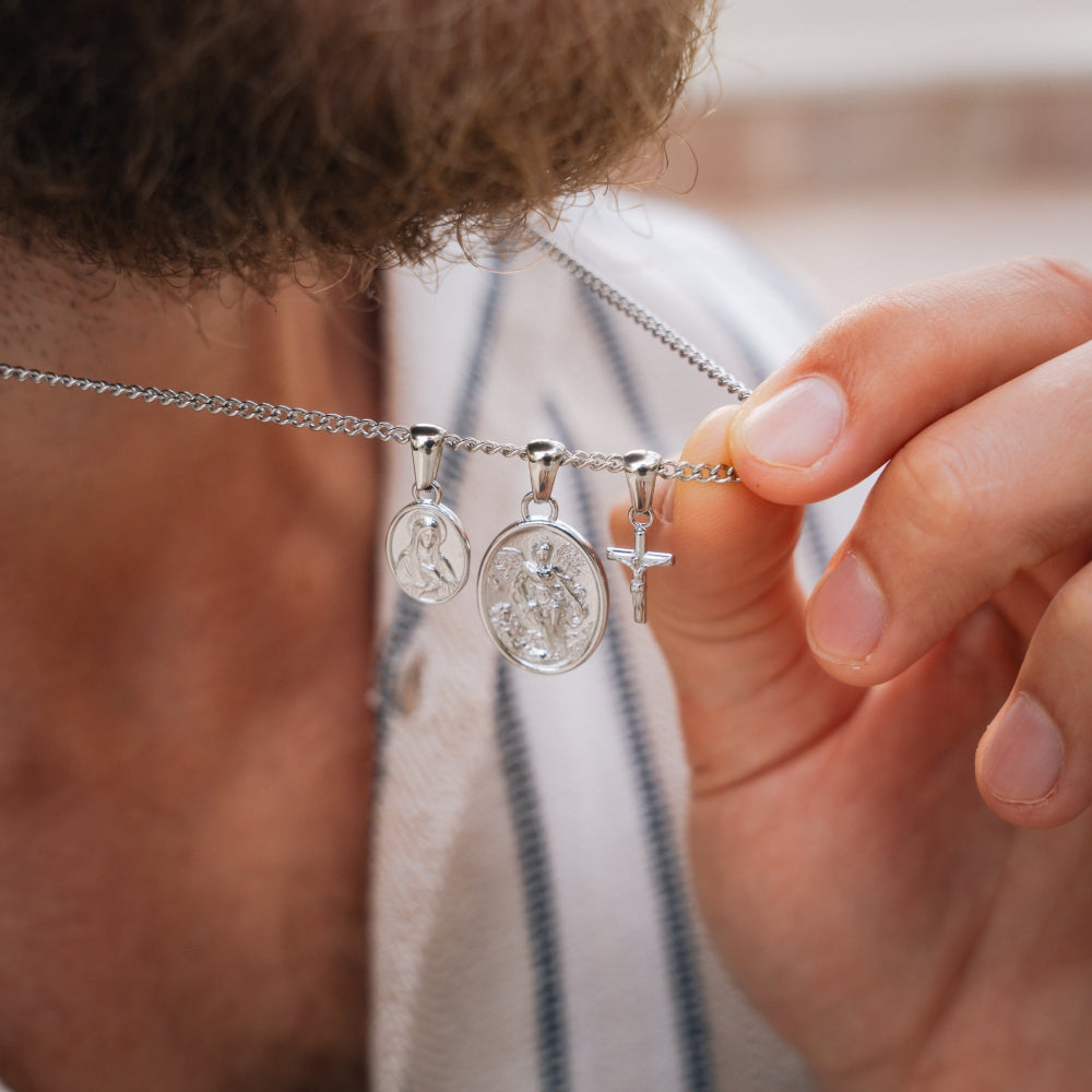 Close-up of a hand holding a silver necklace with three pendants.