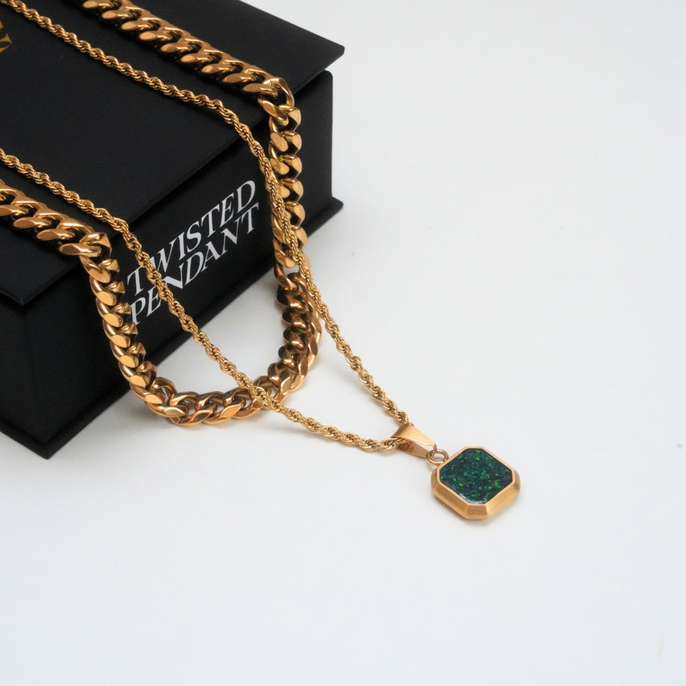 Gold chain necklace with a green pendant on a white surface