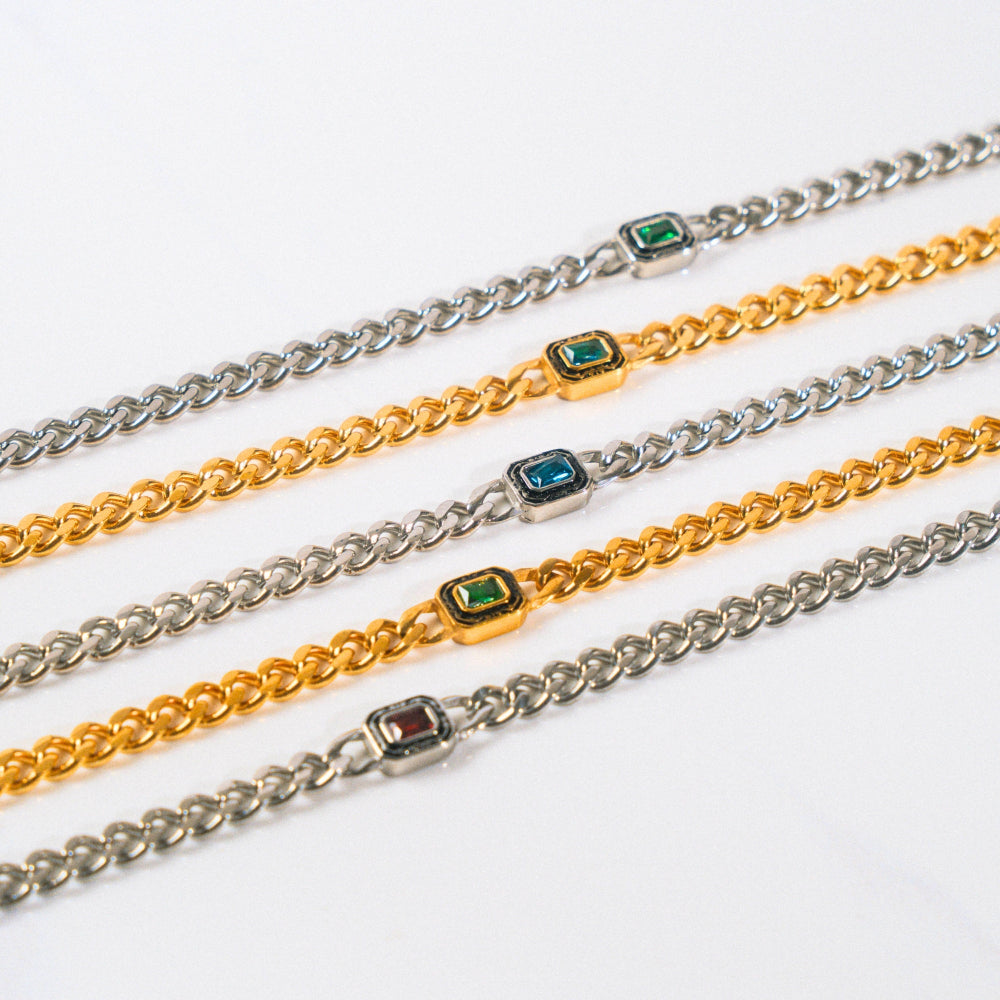 Three chain bracelets with gemstone accents on a white background