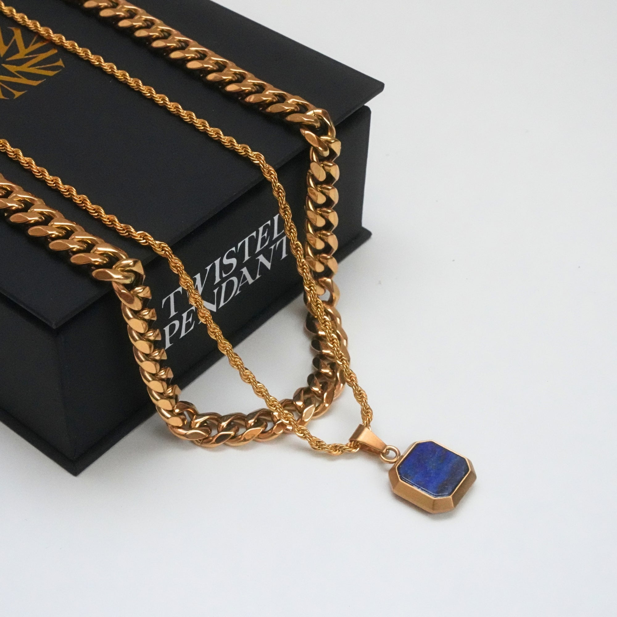 Gold chain necklace with a blue pendant on a white background