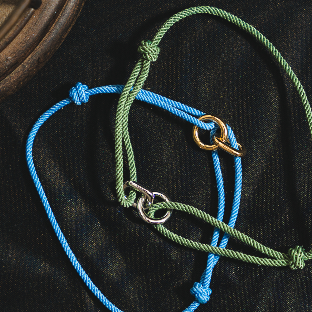 Two braided ropes, one blue and one green, with metal clasps on a black background.