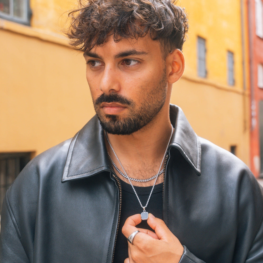 Man wearing a black leather jacket with a yellow building in the background