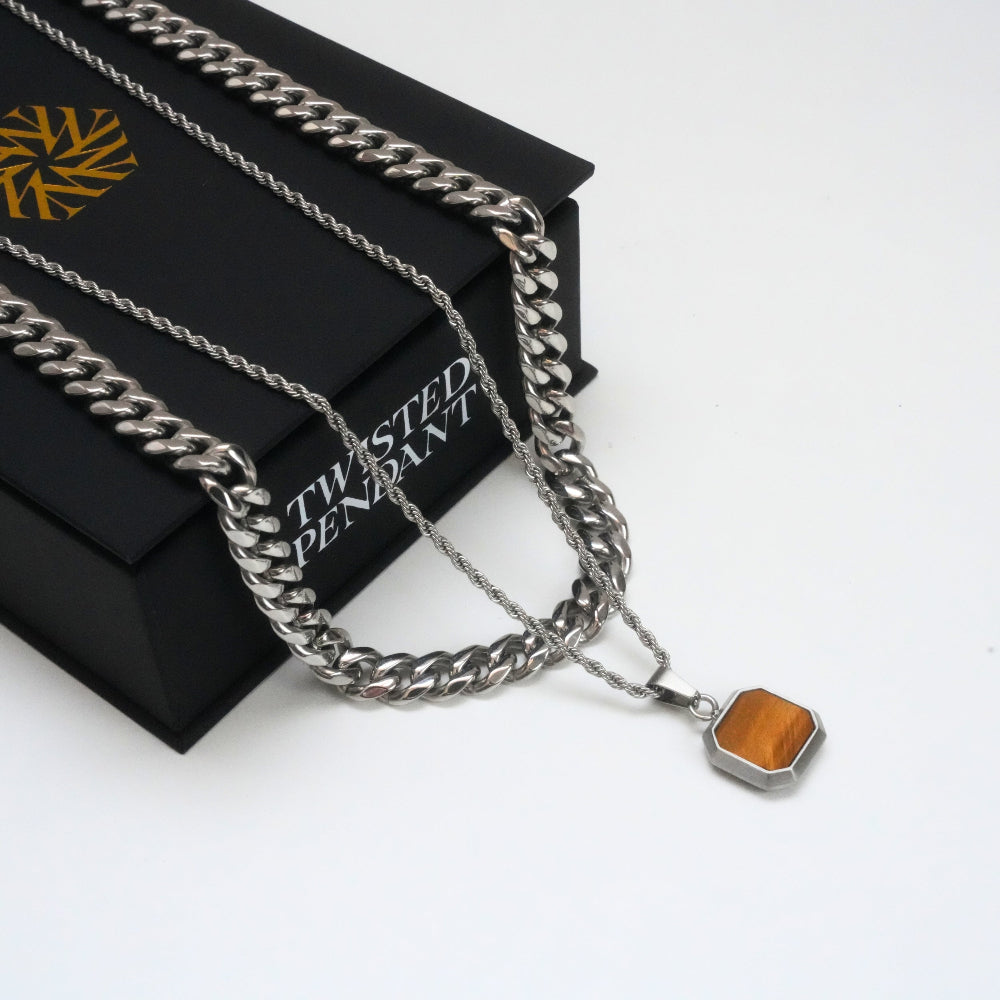 Silver chain necklace with a tiger eye pendant on a black box labeled 'Twisted Pendant'.