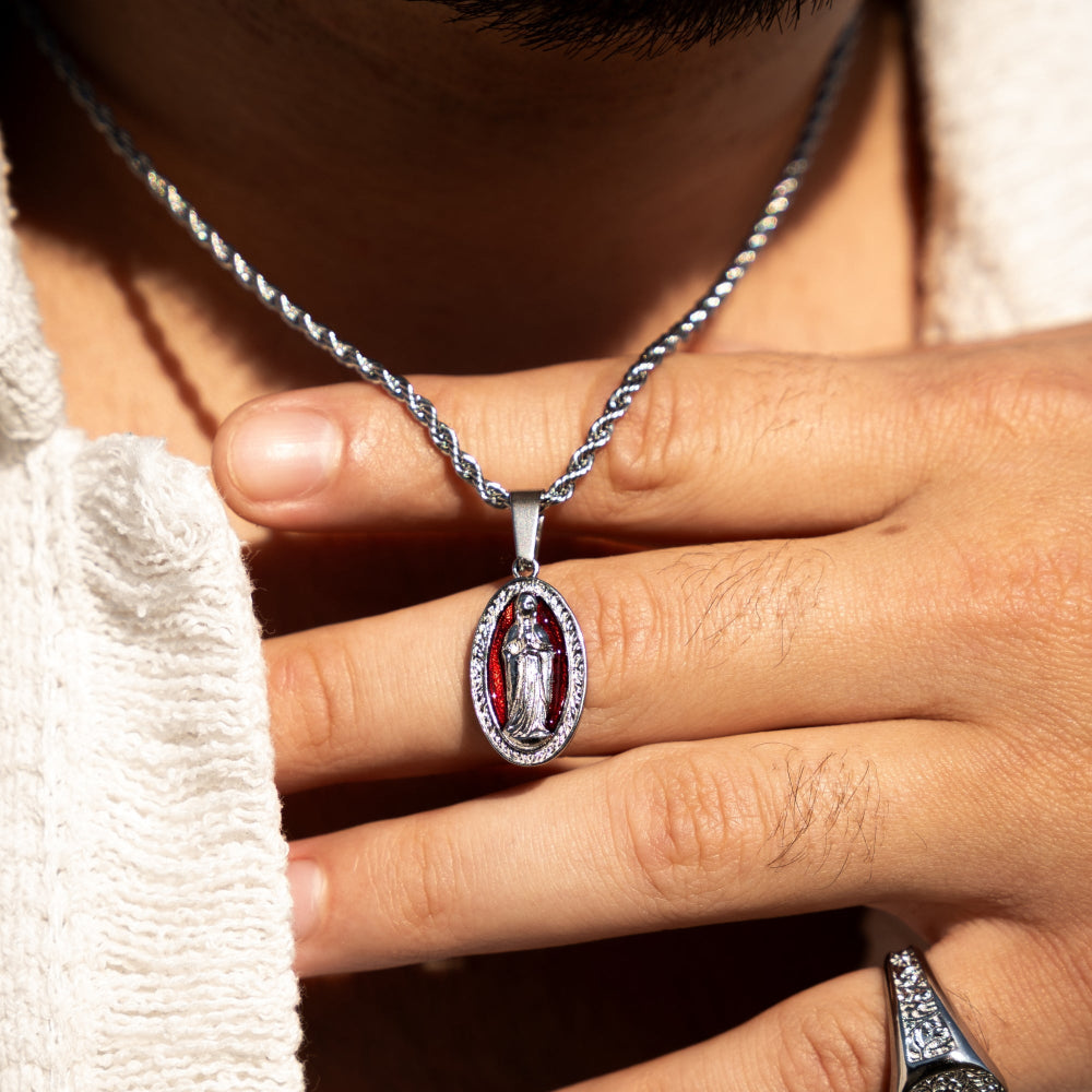 Close-up of a hand wearing a silver necklace with a pendant.