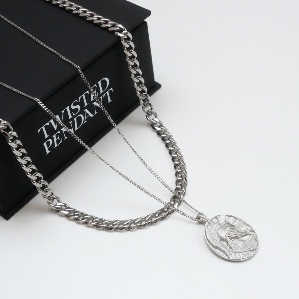 Silver chain necklace with a pendant on a white surface next to a black box labeled 'Twisted Pendant'.