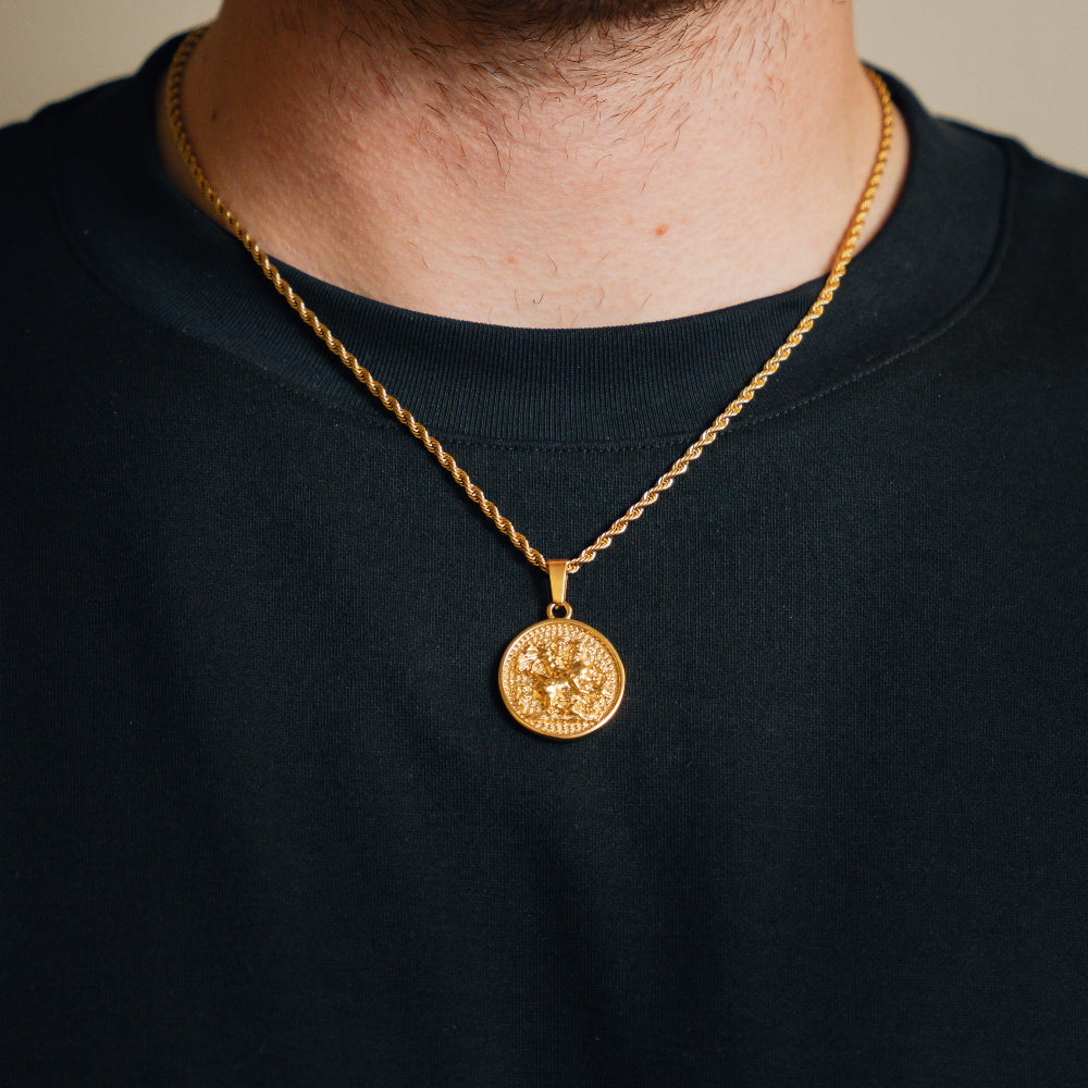 Gold necklace with a pendant worn by a person on a black background
