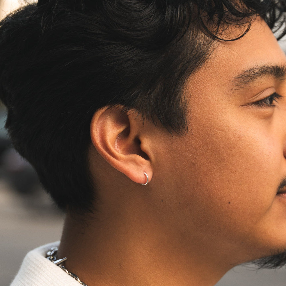 Close-up of a person wearing a silver hoop earring with a blurred background