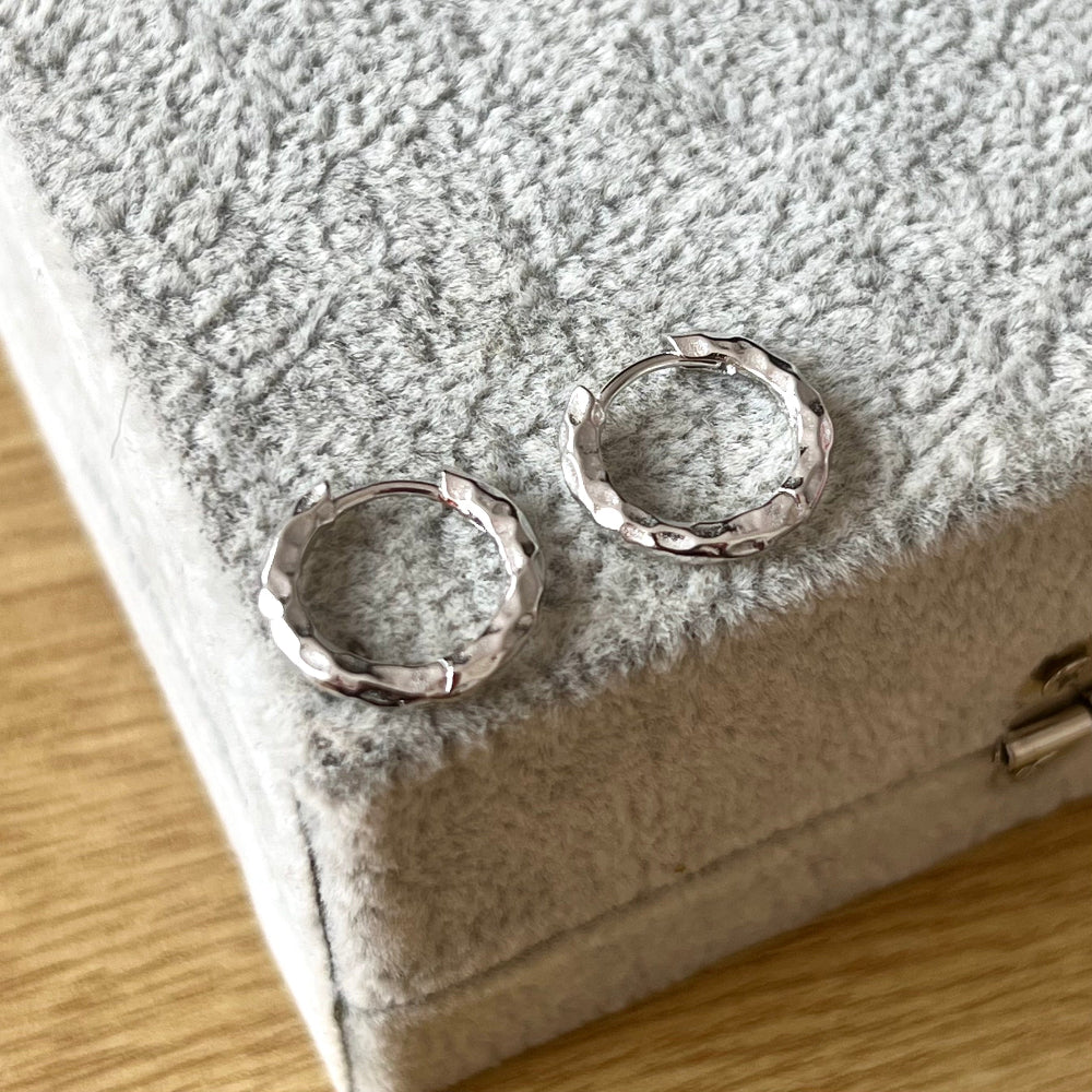 Silver hoop earrings on a textured gray surface