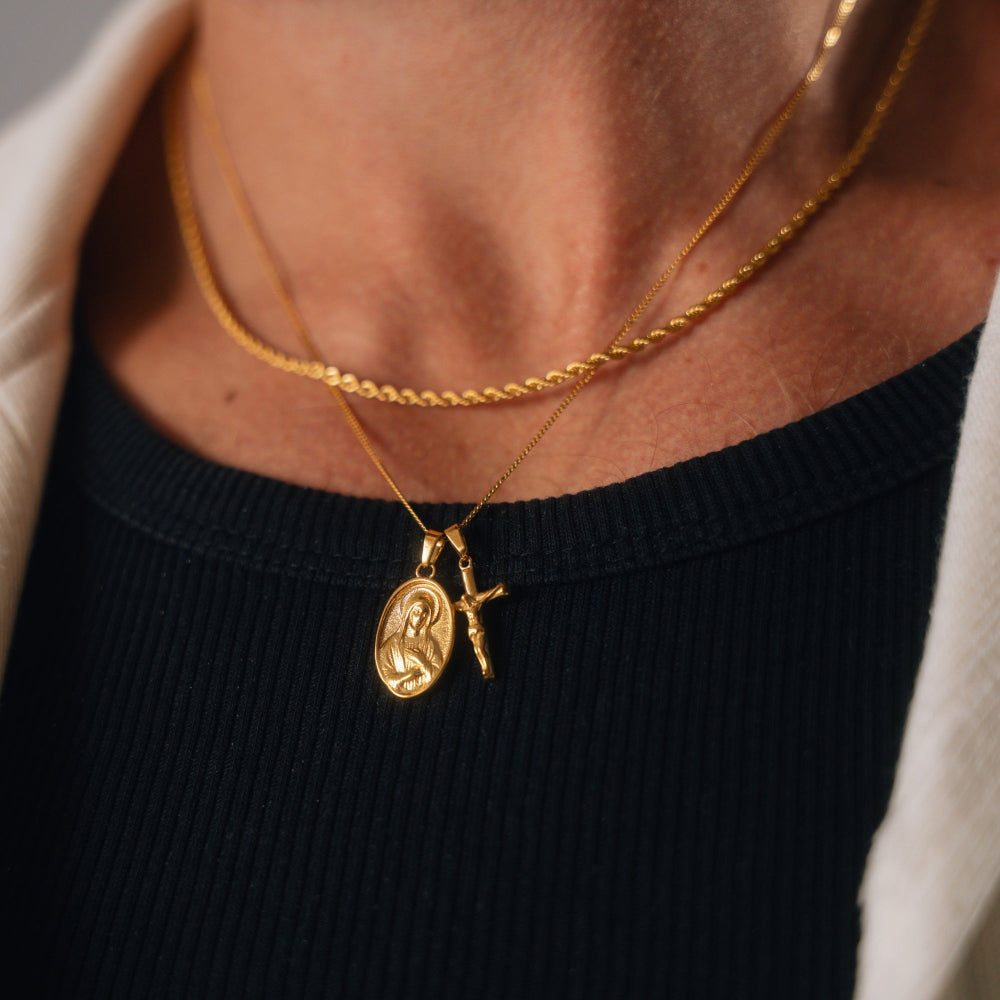 Gold necklace with a pendant worn by a person against a neutral background
