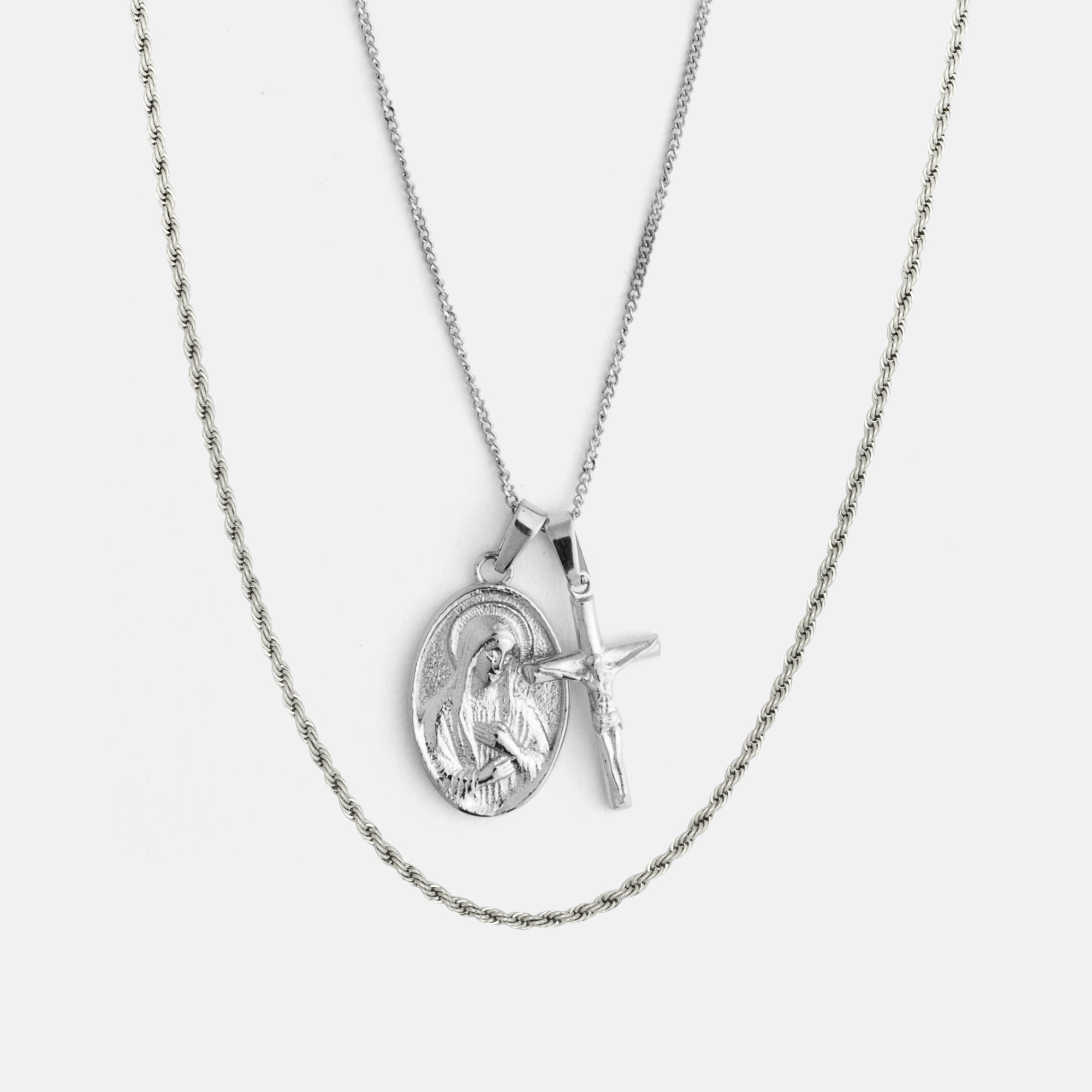 Silver necklace with a heart-shaped pendant and cross on a light gray background