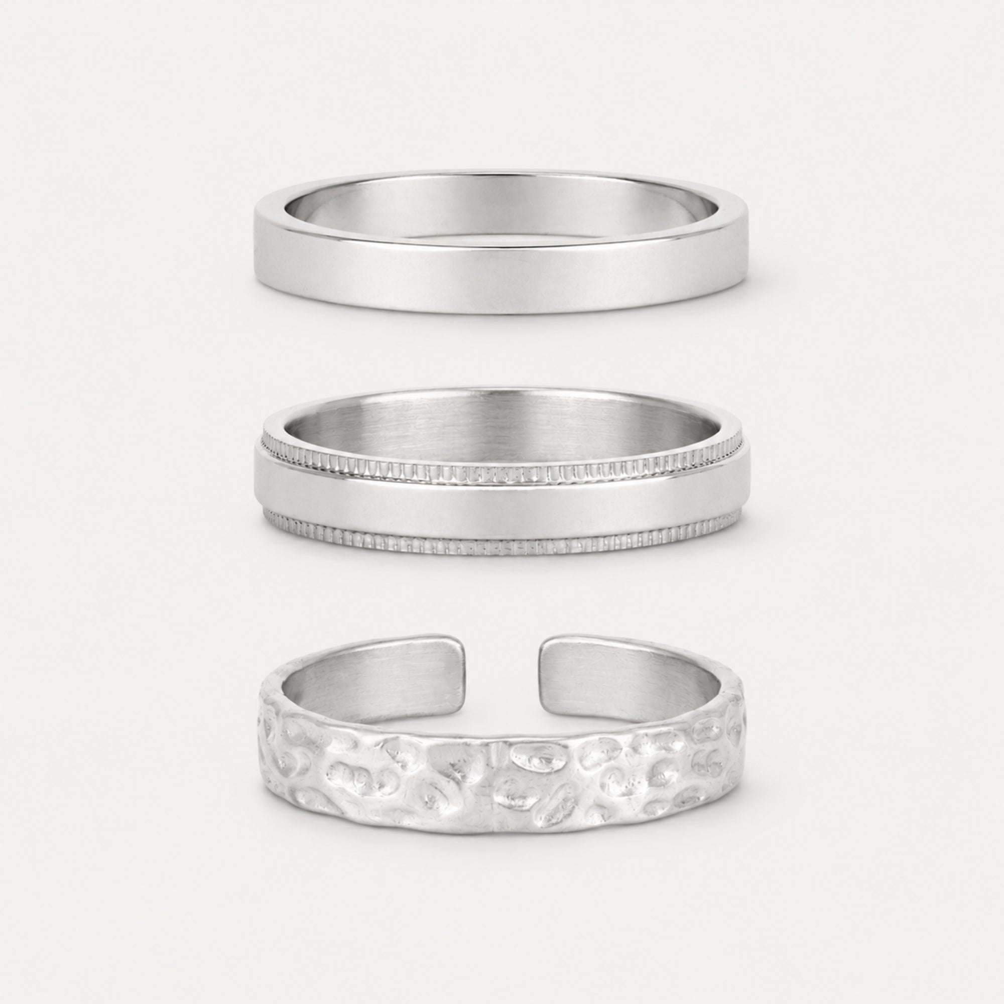 Three silver rings with different designs on a light gray background