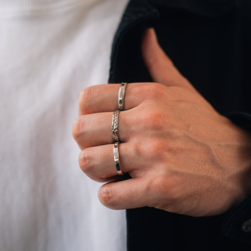 Close-up of a hand wearing two silver rings with a blurred background