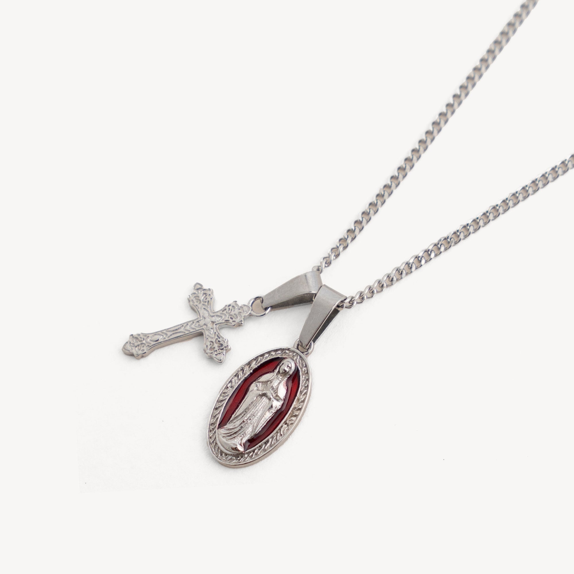 Silver necklace with a cross pendant and a pendant featuring a religious figure on a white background
