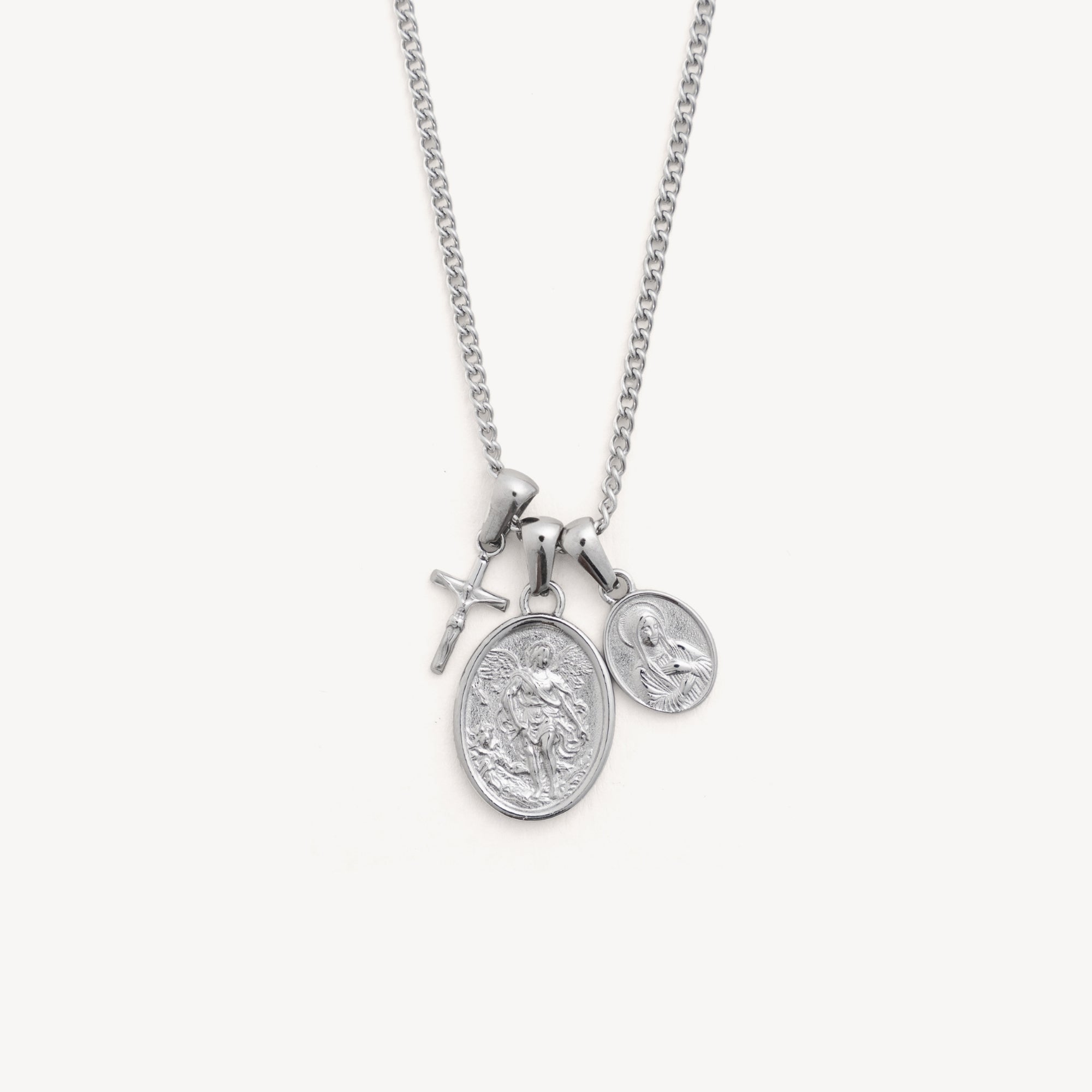 Silver necklace with two round pendants and a cross on a white background
