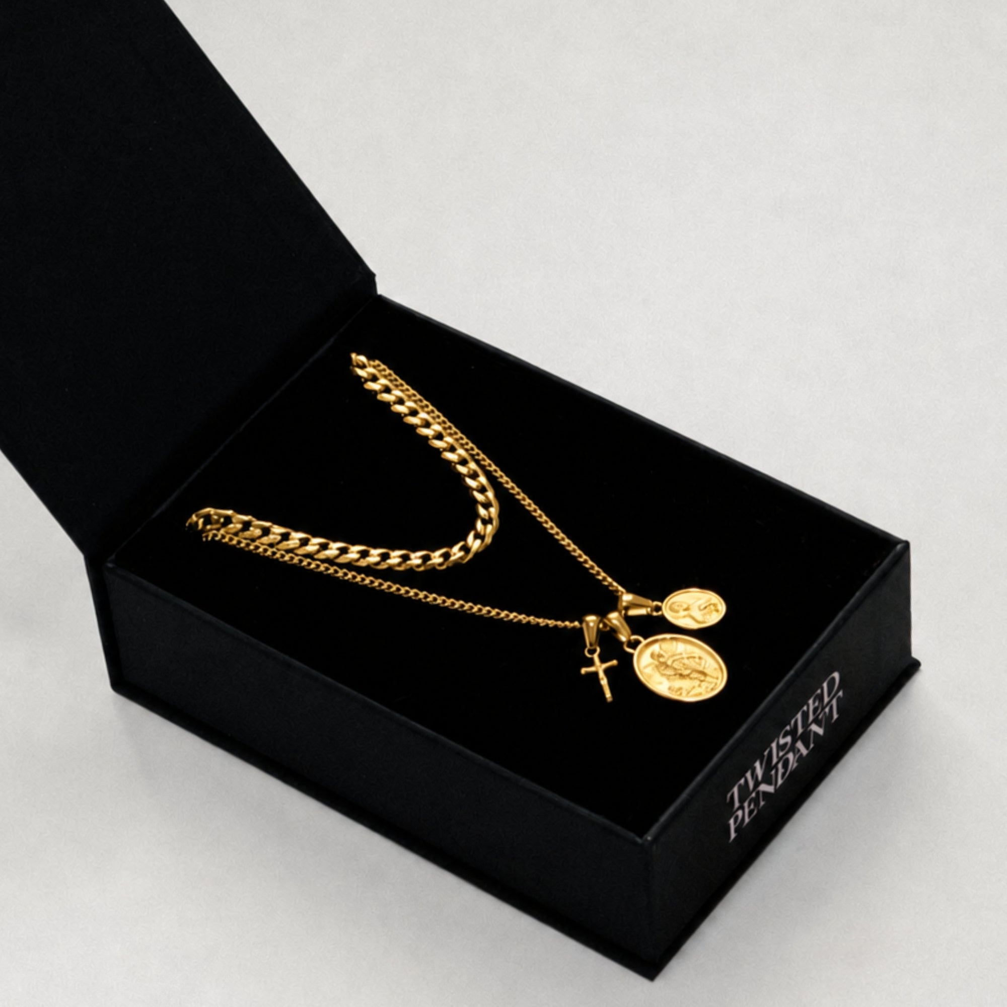 Gold necklace with pendants in a black jewelry box on a light gray background