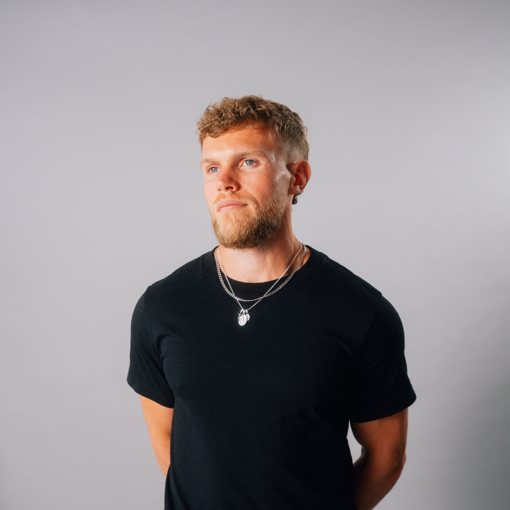 Man wearing a black t-shirt against a gray background