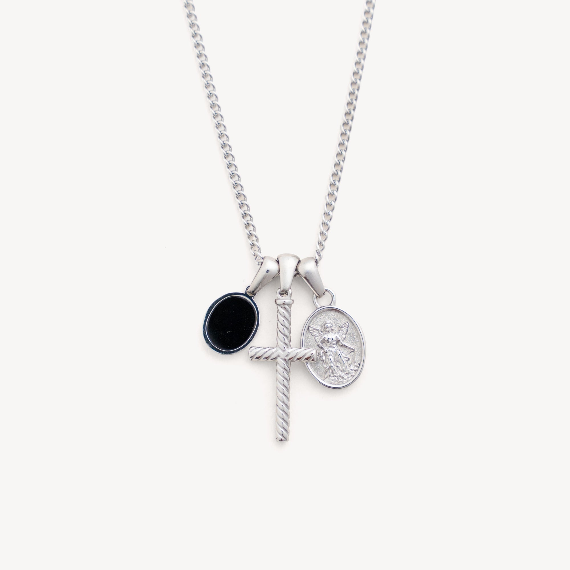 Silver necklace with three charms on a white background