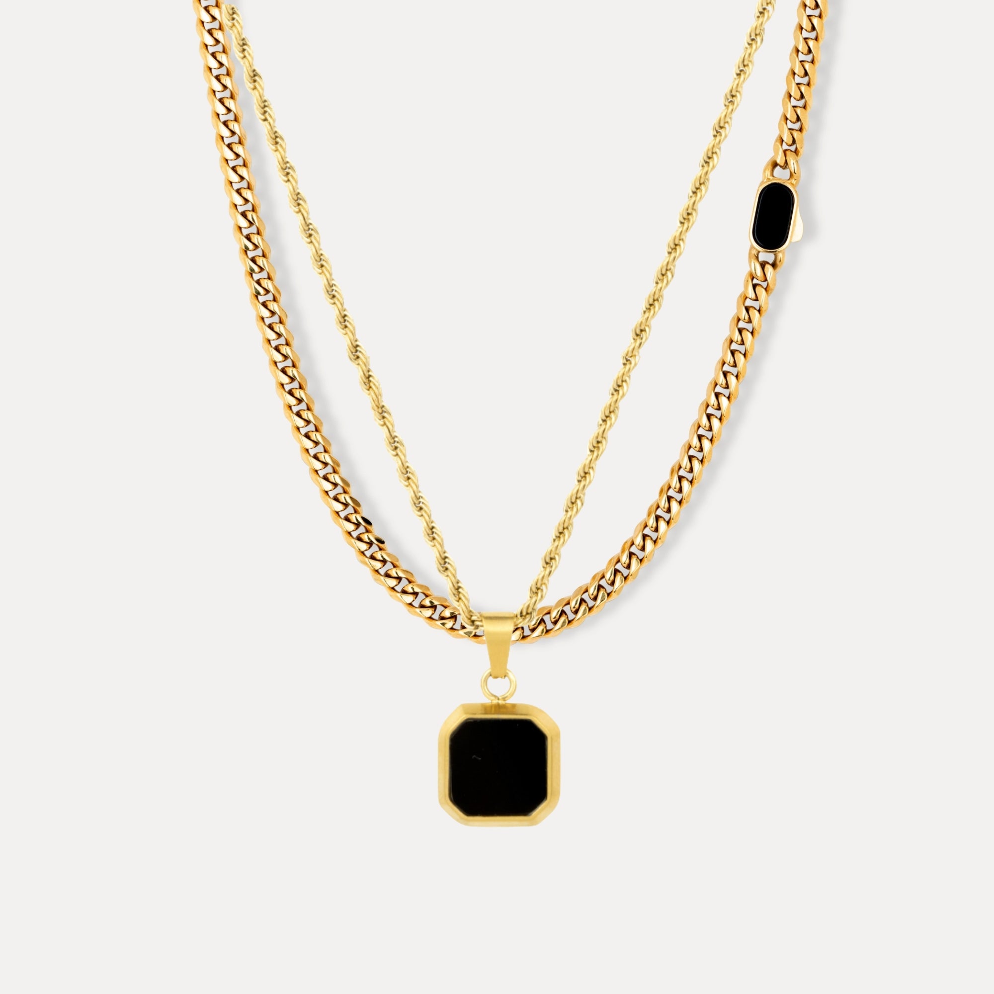 Two gold necklaces with black pendants on a white background