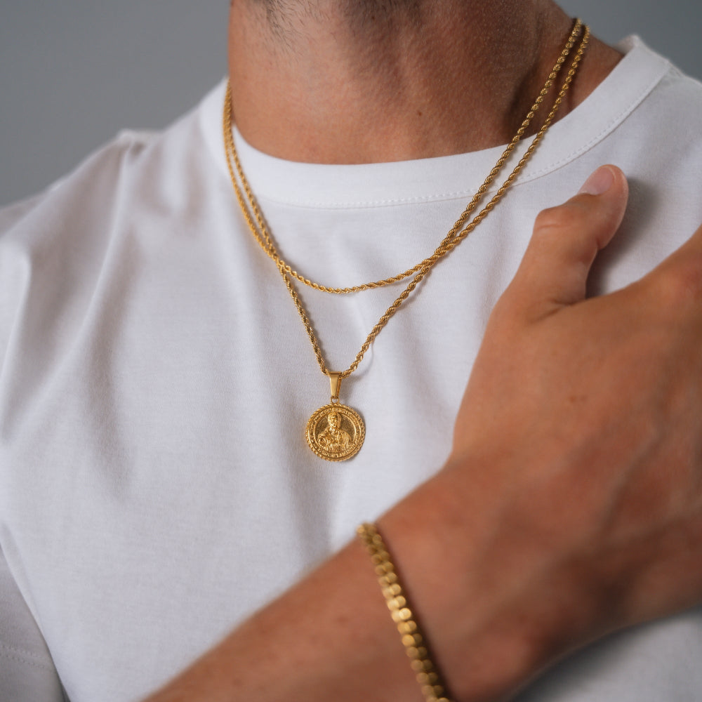 Person wearing a gold necklace and bracelet on a plain background